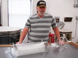 A fascinating use of nested coils in this condenser . A man demonstrates the large condenser.